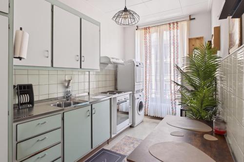 a kitchen with white cabinets and a sink and a table at Bistro Walk Apartment in Lausanne