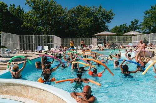 a group of people in the water at a swimming pool at ZEcamping 4 étoiles avec parc aquatique - sauna et hammam in Sanguinet