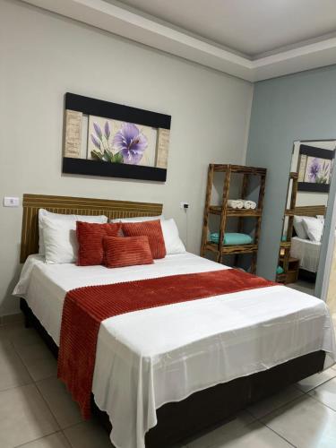 a bedroom with a large white bed with red pillows at Pousada Fênix,com piscina -250 METROS DA PRAIA in Pontal do Paraná