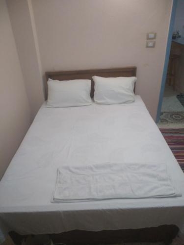a bed with white sheets and pillows in a room at Fekry house in Qaryat Ḩātim aţ Ţāʼī