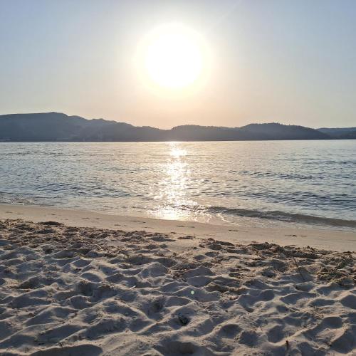a beach with the sun rising over the water at AL Tróia Penaferrim in Troia