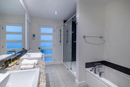 a white bathroom with two sinks and a shower at Les Immeubles Charlevoix - Le 760-415 in Quebec City