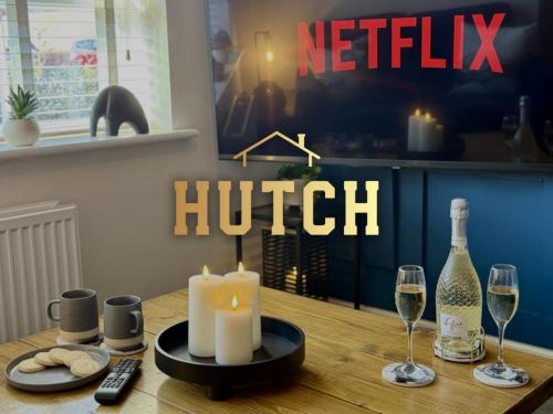 a table with a candle and two glasses of wine at Modern 2-Bed House with EV - Hosted by Hutch Lifestyle in Warwick