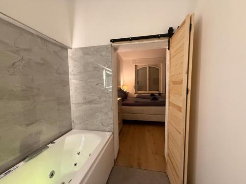 a bathroom with a bath tub and a bedroom at 35qm2, Whirlpool & Queensize-Bett, Terrasse 50qm2, Self-Checkin, eigener Parkplatz, Nähe Ulm und Universität in Blaustein