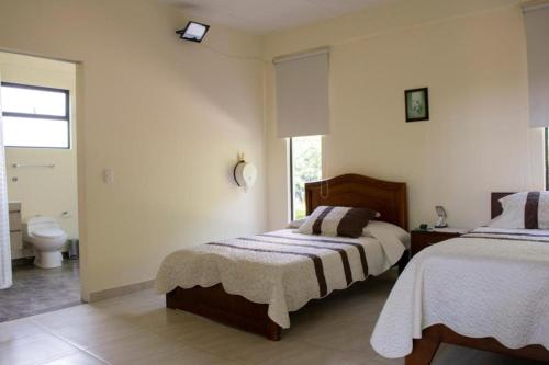 a bedroom with two beds and a bathroom at Villa Romero Hospedaje in Vergara