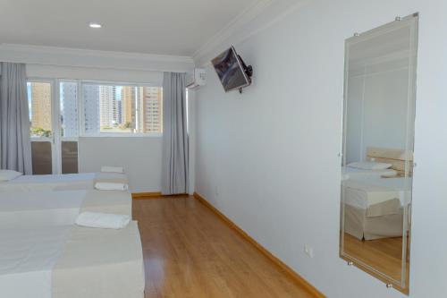 a white bedroom with a mirror and a bed at Harbor Buriti Hotel in Campo Grande