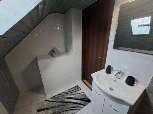 a bathroom with a sink and a shower with a staircase at Kakukkfészek Apartmanok in Kiskunmajsa