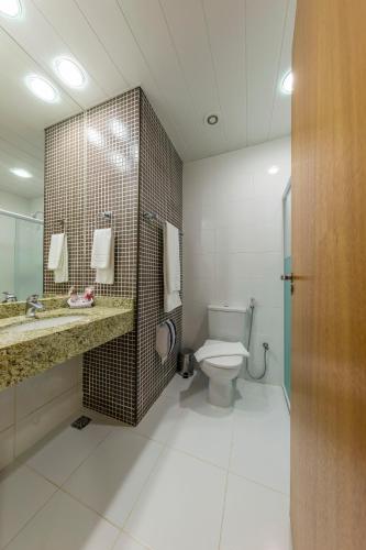 a bathroom with a toilet and a sink and a mirror at Hotel Thomasi Express in Maringá