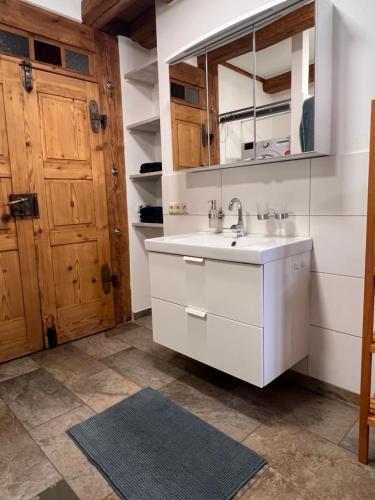 a bathroom with a sink and a wooden door at Ferienwohnung Hansnhof in Wilhelmsthal