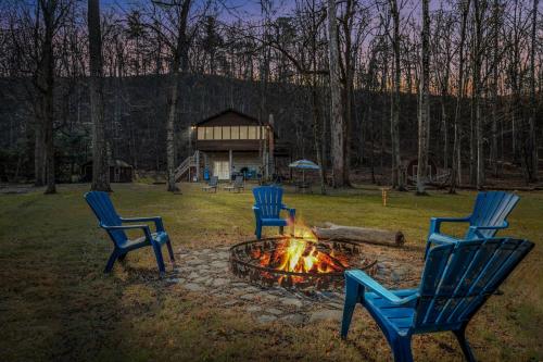 three chairs sitting around a fire in a yard at Khan River Cabin in Great Cacapon