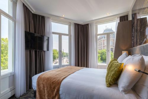 a hotel room with a large bed with windows at Leonardo Hotel Amsterdam Museum Quarter in Amsterdam