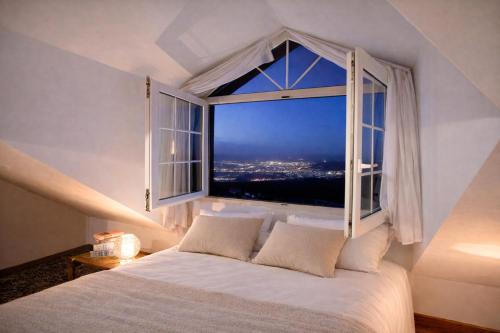 a bedroom with a large window with a white bed at Hotel El Balcon de las nieves in La Zubia