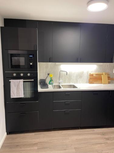 a kitchen with black cabinets and a sink and a microwave at Modern apartment - Balcony, Parking, BBQ in Vossevangen