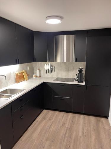 a kitchen with black cabinets and a sink at Modern apartment - Balcony, Parking, BBQ in Vossevangen