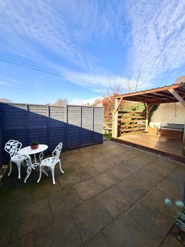a patio with two white chairs and a table at 3 bedroom cottage Brecon sleeps 4 in Brecon