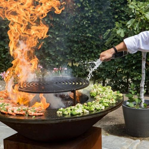 a person is cooking food on a grill with fire at Azor'Oasis in Calhetas