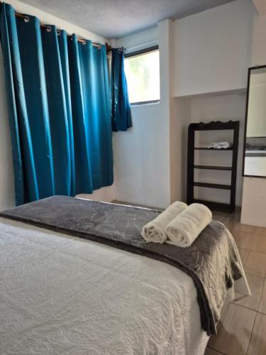 a bedroom with a bed with blue curtains and towels at Home Garden in San Pedro La Laguna
