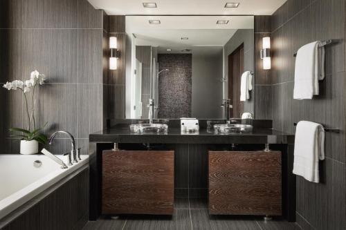 a bathroom with a sink and a tub and a mirror at The Joule Dallas in Dallas