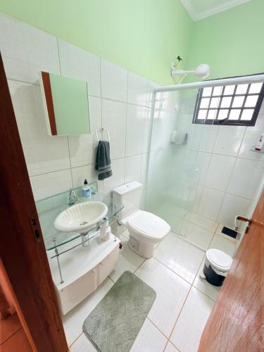 a white bathroom with a toilet and a sink at Chacara Vale do Barreiro in Taubaté