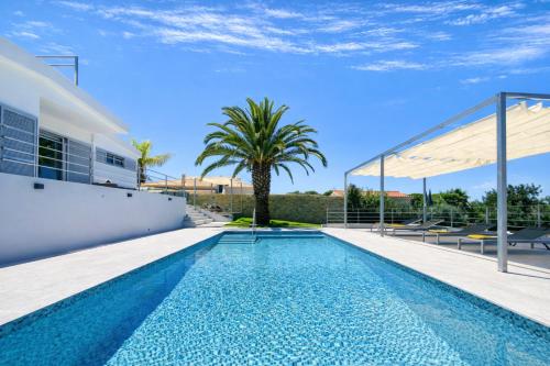 a swimming pool in the backyard of a house with a palm tree at Moderna - Private Pool - 8 Guests - Quarteira in Quarteira