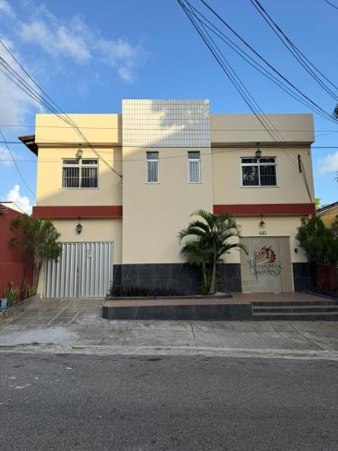 a white house with a palm tree in front of it at Residencial Dragão in Fortaleza