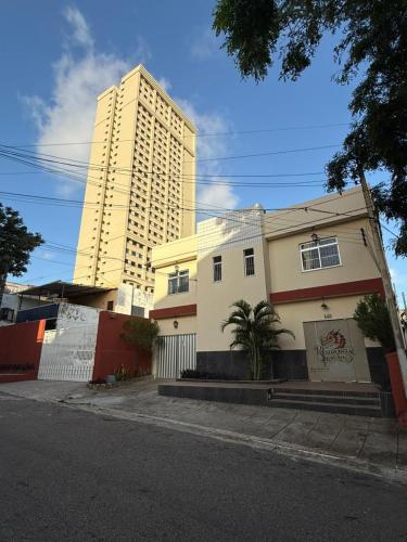 a tall building in front of a white house at Residencial Dragão in Fortaleza