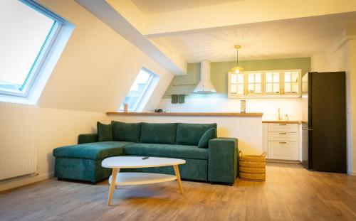 a living room with a green couch and a table at Le #7 - Centre ville - Parking privé - Balcon in Saint-Omer