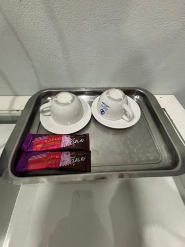 a tray with two cups and plates and a book at KaizaHotel Suvarnabhumi Airport in Lat Krabang
