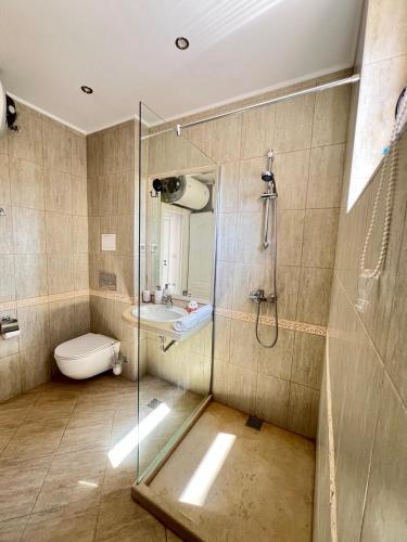 a bathroom with a shower and a toilet and a sink at La Mer Prime Time in Varna City