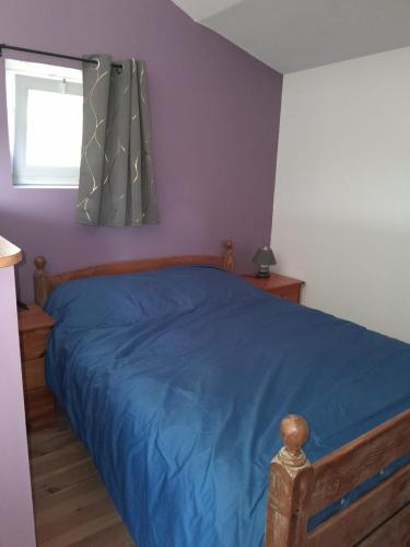 a bedroom with a blue bed with a window at 35 m2 independent studio in Marillet