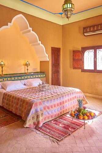 a bedroom with a bed with a tray of fruit on the floor at Hotel Kasbah Azalay in Mhamid