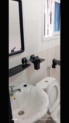 a bathroom with a sink and a toilet and a mirror at Les studios américains d'Angré - 2 in Mandanou