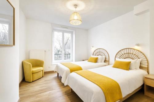 two beds in a white room with a yellow chair at Au jardin de la Basilique in Boulogne-sur-Mer
