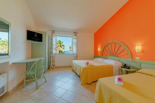 a bedroom with two beds and an orange wall at Hotel Villaggio Cala Di Volpe in Capo Vaticano
