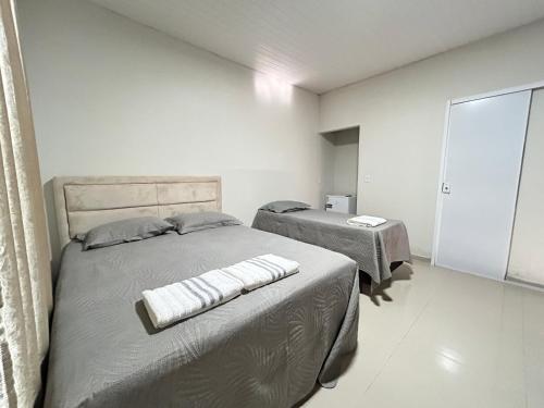 a white bedroom with two beds and a window at Pousada Morada Nobre in Barreirinhas