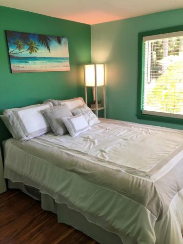 a large bed in a bedroom with a green wall at Royal Palm Cottage Hawaii in Hakalau