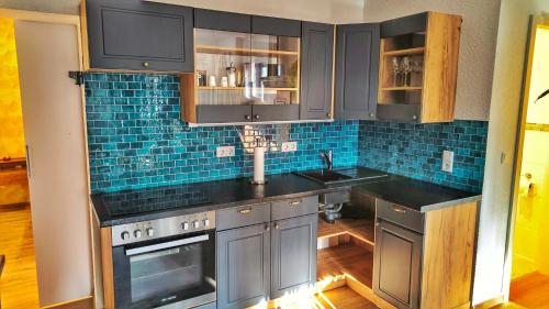 a kitchen with black cabinets and blue tile at AMORE 69 bei Greta in Marl