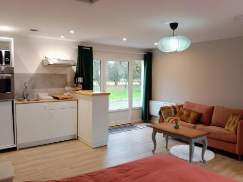 a kitchen and living room with a couch and a table at Studio nature indépendant in Le Gâvre