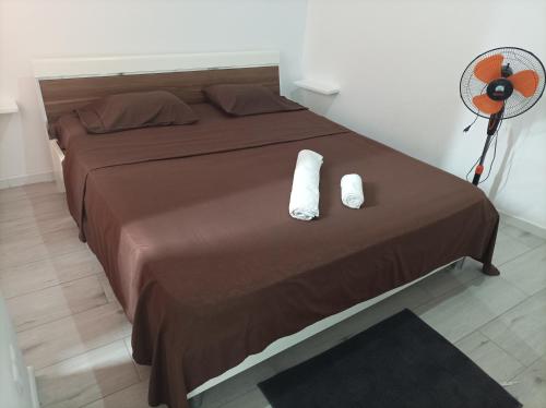 Una cama con dos toallas blancas y un ventilador. en LBranco, en Porto Novo