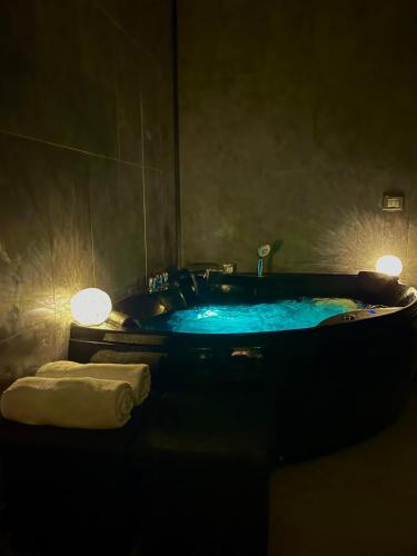 a dark bathroom with a tub with blue water at Artemide Resort Spa - Private Villa in Lido Di Fondi