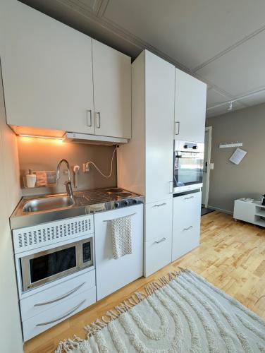 a kitchen with white cabinets and a sink at Private Studio with Bathroom and Kitchen, Central Location in Tromsø