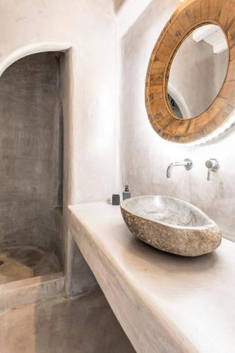 a bathroom with a stone sink and a mirror at Boutique Villa Aquata Private pool in Mikonos