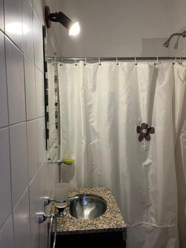 a bathroom with a sink and a shower curtain at Departamento espiral in Embalse