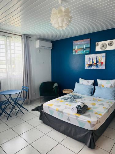 a bedroom with a large bed with a blue wall at LE ROSA PARKS CLÉMARTHA in Kourou