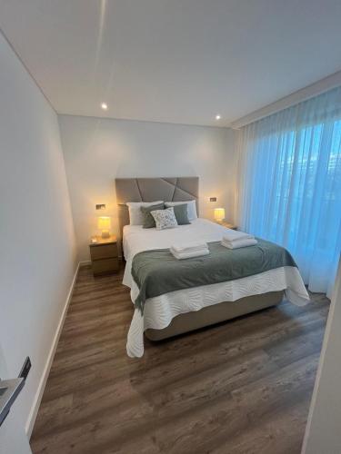 a bedroom with a large bed and blue curtains at NEW Apartment, Sea Front & Shared Pool in Quarteira