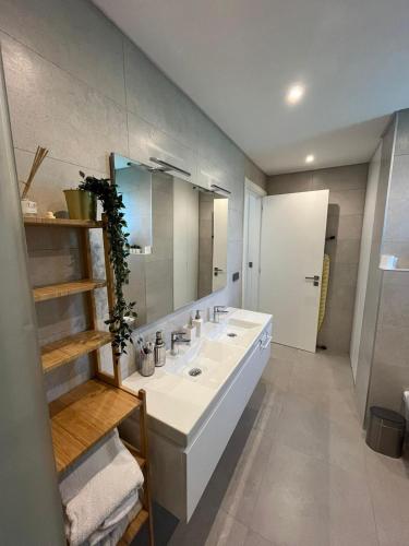 a bathroom with a white sink and a mirror at NEW Apartment, Sea Front & Shared Pool in Quarteira
