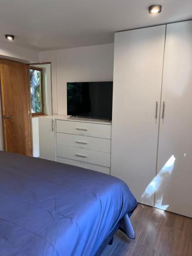 a bedroom with a bed and a flat screen tv at Tranquila y moderna en el bosque in San Carlos de Bariloche