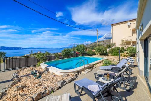a swimming pool with chaise lounge chairs next to a house at Villa The Sunset View in Nehaj