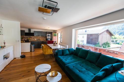 a living room with a green couch and a large window at Gemütliches Gästezimmer mit gemeinsamer Küche, Wohnzimmer & Balkon in Nassereith