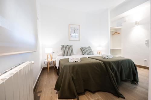 a white bedroom with a bed and a table at EL COLLELL - Complejo Familiar in Sant Ferriol